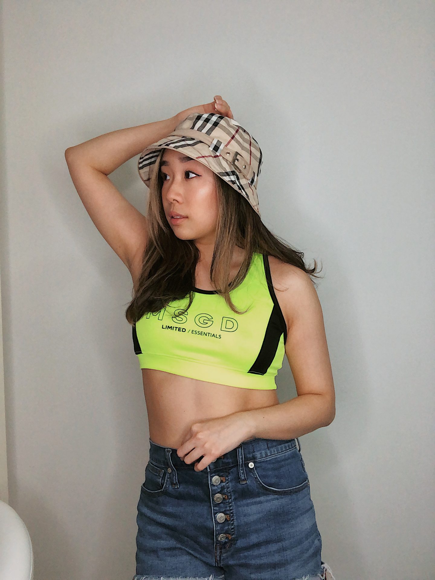 plaid bucket hat paired with jean shorts and a neon top