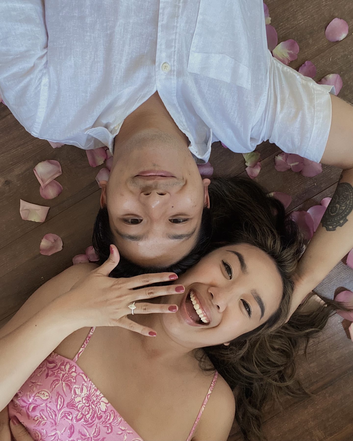 Girl and boy lying down on floor with girl showing her engagement ring