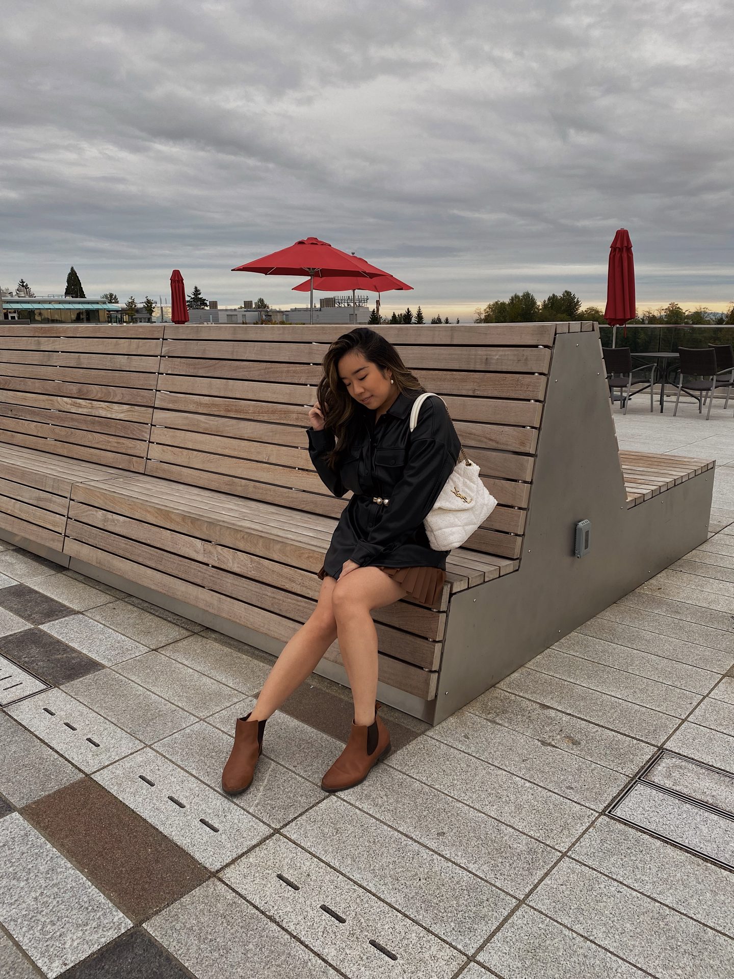 Girl wearing fall look of black leather jacket, white purse and brown leather boots 