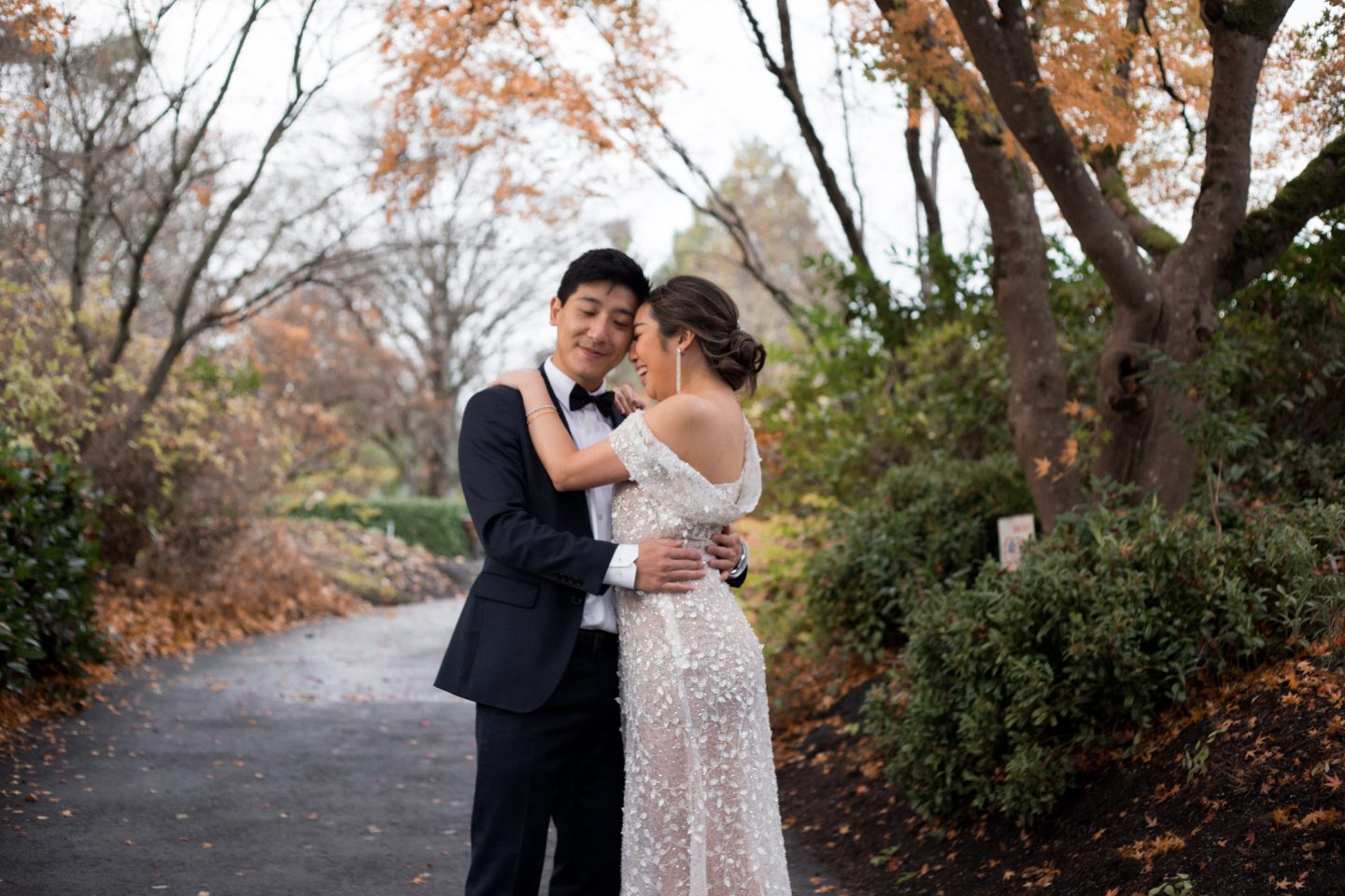 a couple in a tux and wedding dress hugging
