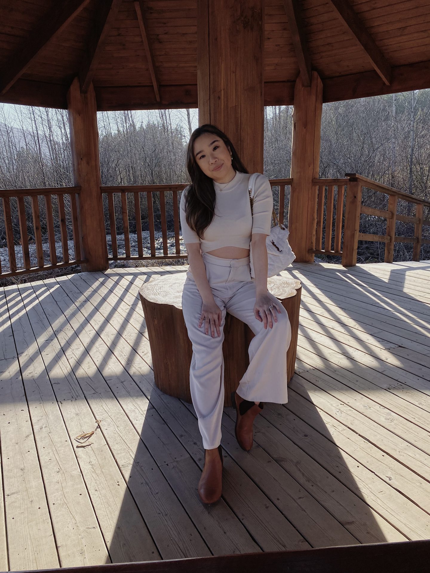 Woman posing on bench with white top and long white pants