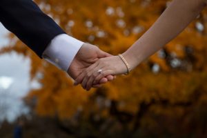 Man and women holding hands with wedding ring in the front of the shot